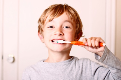 Boy brushing teeth with orange toothbrush